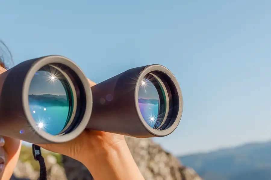 Frau hält Fernglas in der Hand und schaut in die Ferne